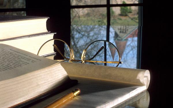 Books and papers on a desk in front of a window